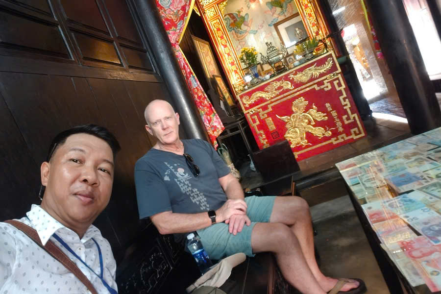 Mr. Viet Nguyen posing with guests inside a traditional ancient house during a Hoi An City Tour on a Central Vietnam Holiday Package.