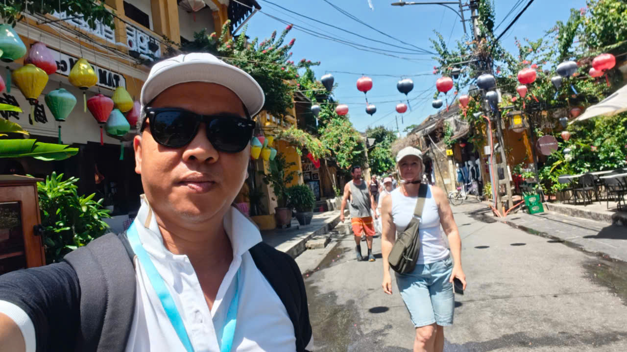 Viet Nguyen taking a selfie with guests during a Hoi An Ancient Town city tour in the historic UNESCO heritage area.