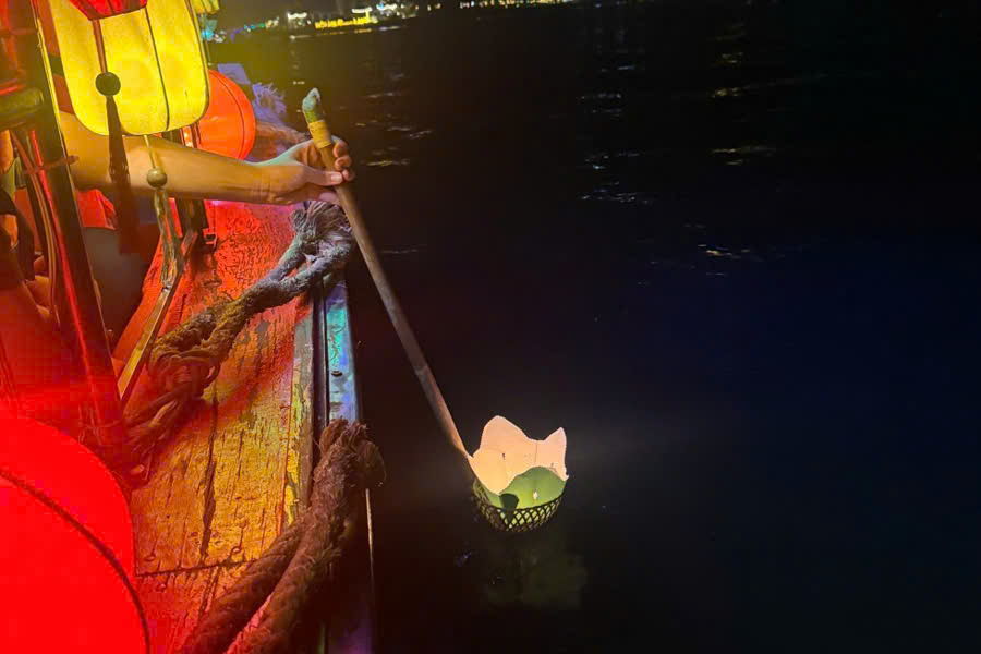 Candle-lit lanterns floating on the Hoai River in Hoi An at night.
