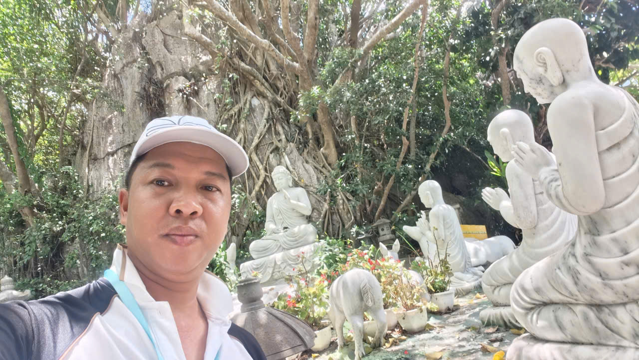 Viet Nguyen takes a selfie in front of Buddhist statues at Marble Mountains
