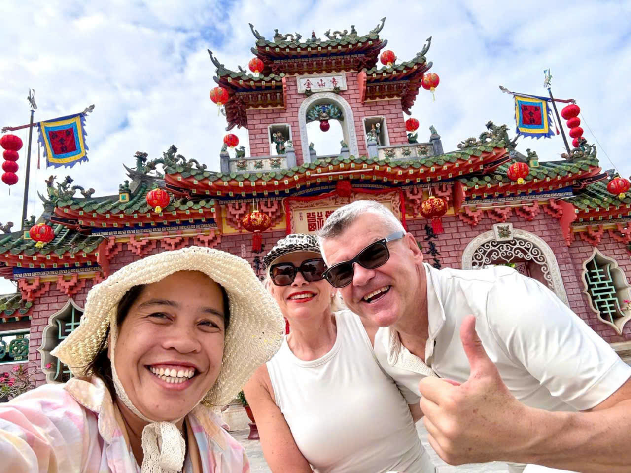 Tour guide taking a selfie with guests in front of Fujian Assembly Hall, Hoi An Ancient Town, Vietnam