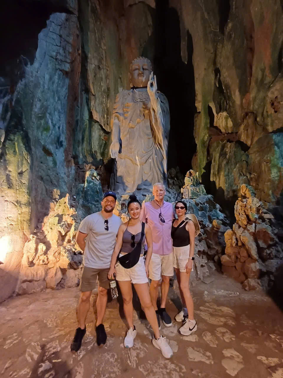 Guests taking photos beside a large Buddha statue inside Tang Chon Cave at Marble Mountains in Da Nang, Vietnam.