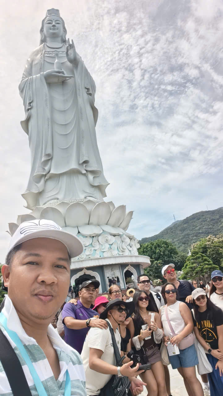 Viet Nguyen taking a selfie with guests in front of the iconic Lady Buddha Statue on Son Tra Peninsula, Da Nang, during a private sightseeing tour.