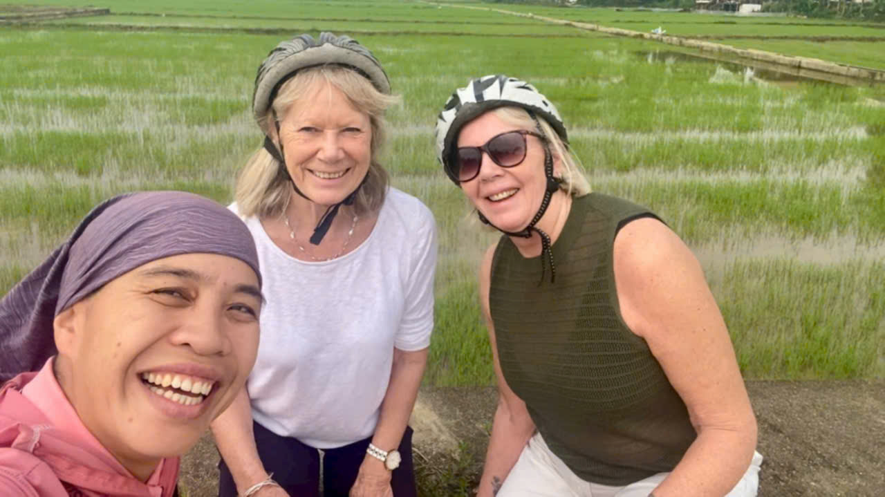 Tour guide posing with guests in front of rice fields during a private Hoi An bicycle tour