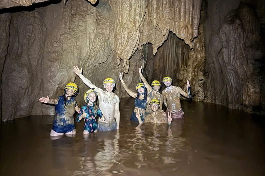 Tourists enjoying a mud bath inside Dark Cave during a tour from Dong Hoi