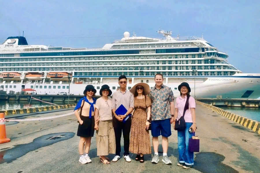 Tour guide taking a photo with cruise guests in front of their cruise ship at Phu My Port before a private Cu Chi Tunnels shore excursion.