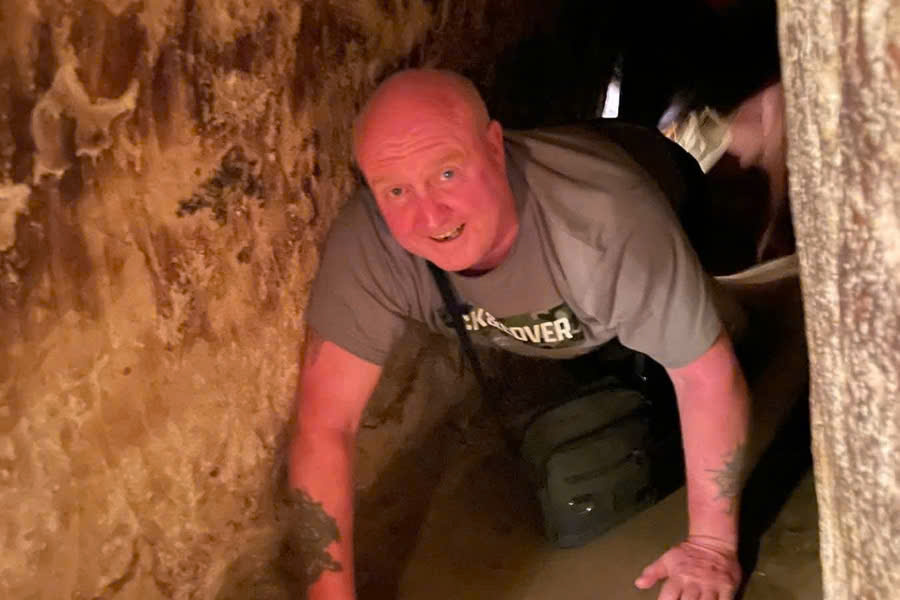 Tourist crawling through a narrow Cu Chi Tunnel during a private shore excursion from Phu My Port.