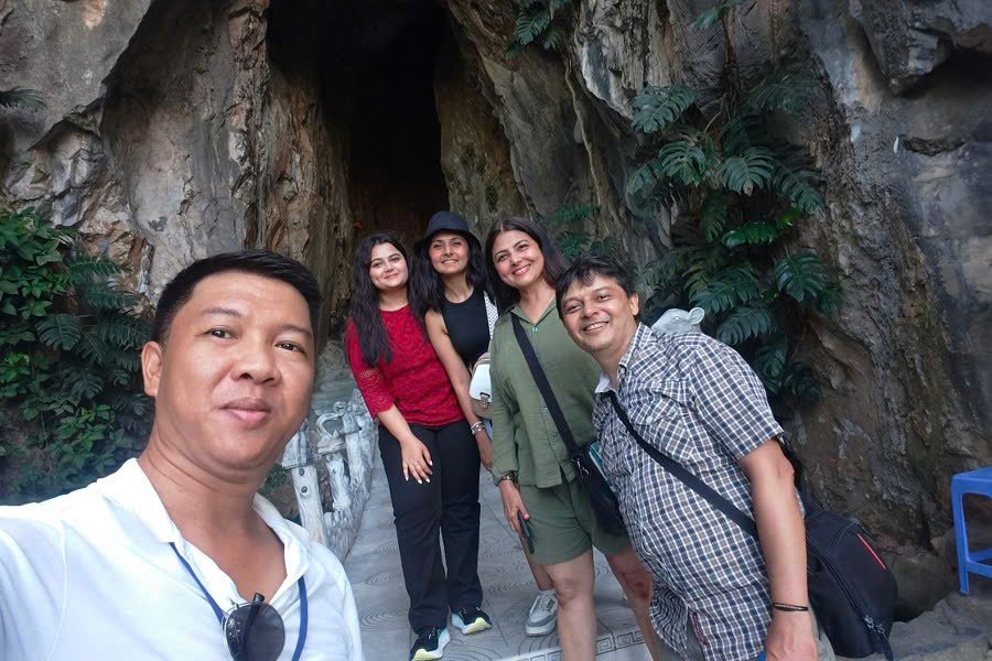 Viet Nguyen taking a selfie with guests in front of a cave