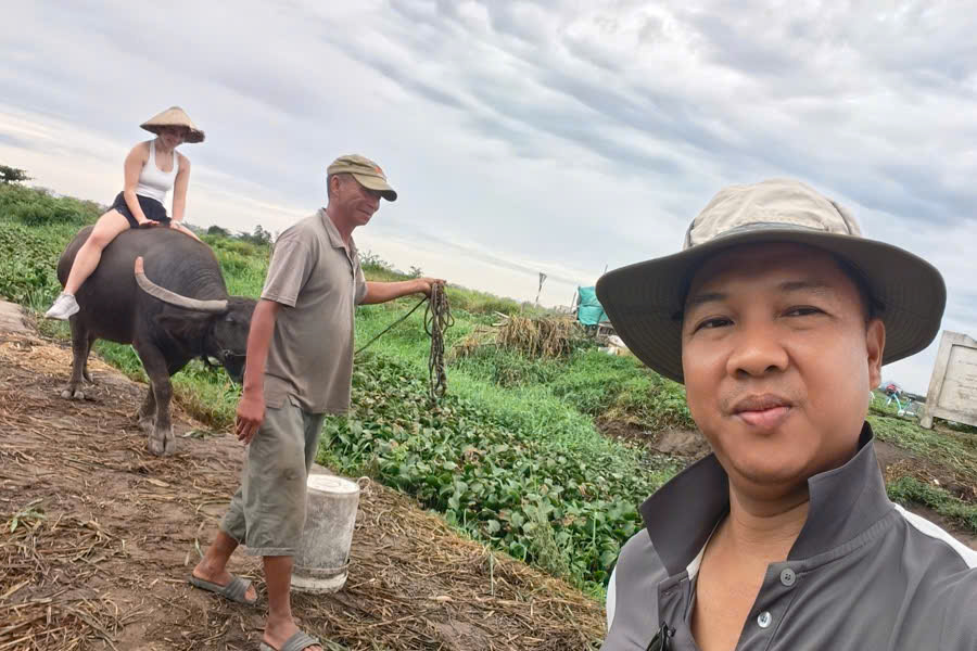 Viet Nguyen taking a selfie with a guest riding a water buffalo in Hoi An countryside