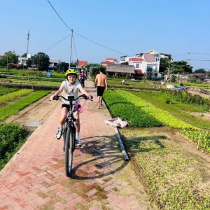 Kid cycling through Tra Que Vegetable Village on a Hoi An Bicycle Tour
