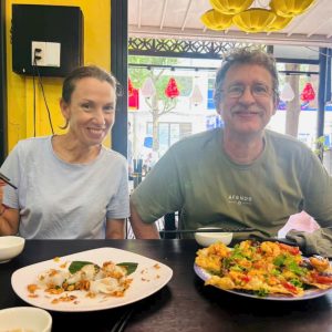 Couple enjoying local street food during a Hoi An Night Street Food Tour before a lantern boat ride on the Thu Bon River