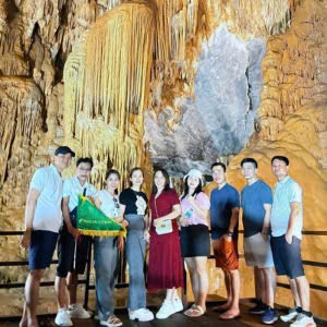 Tour guide taking photos with a group of travelers inside Phong Nha Cave, Vietnam